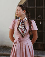 Model trägt Dirndl Magnolia in Altrosa vor historischer Kulisse